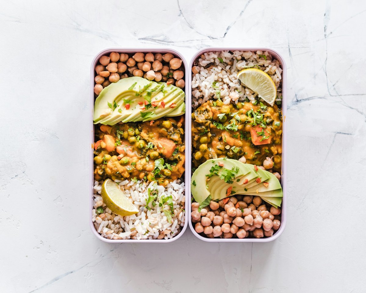 Boîte repas garnie de pois chiches, de riz, d'avocat et de quartiers de citron vert