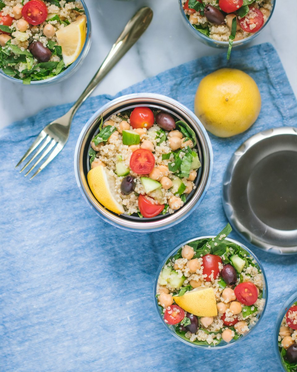 Salades de céréales et de pois chiches présentées en bocaux de verre sur une nappe bleue