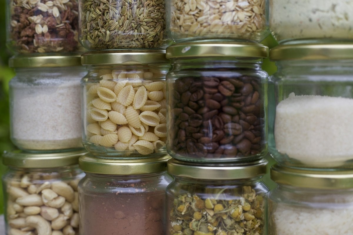 Bocaux en verre empilés contenant noix de cajou, pâtes, café en grains, riz et graines